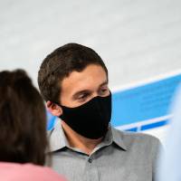 Scholar wearing mask giving poster presentation to a guest.